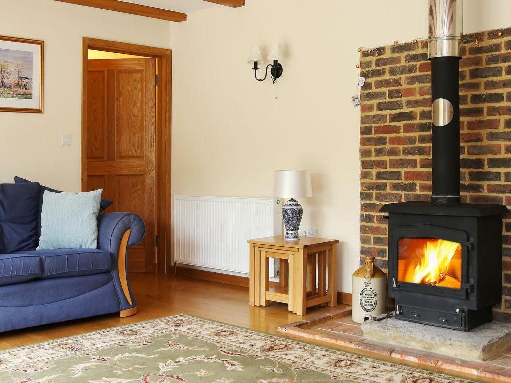 a living room with a fireplace and a blue couch at Cowslip Cottage in Brook