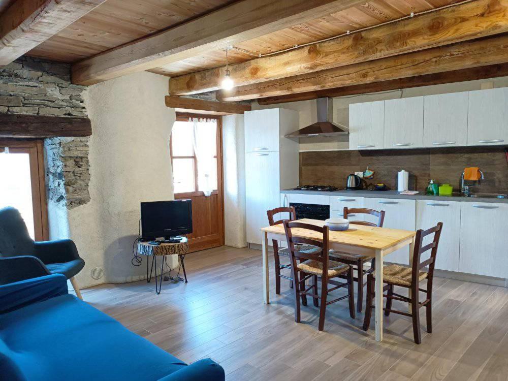 uma cozinha e sala de jantar com mesa e cadeiras em Casa Vacanze Nebin em Stroppo