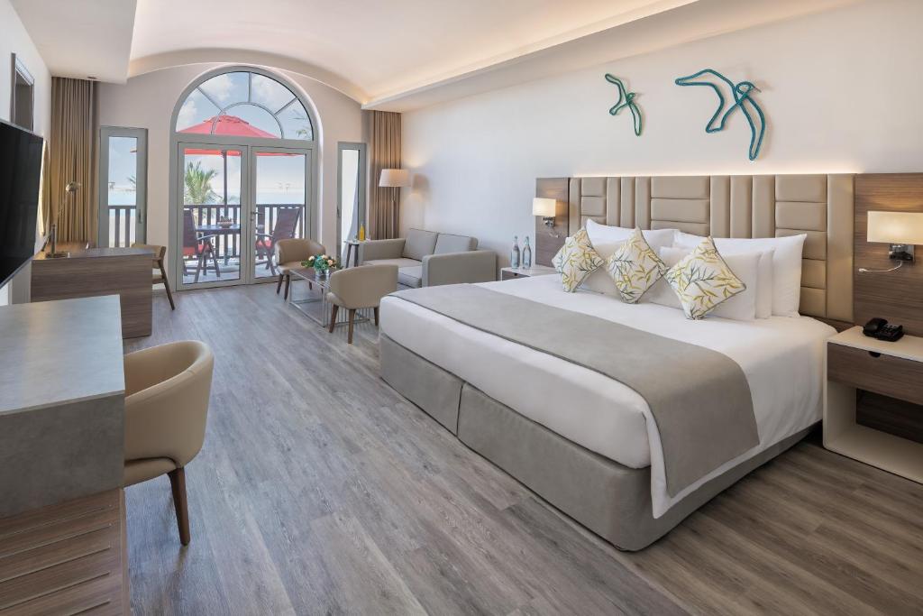a hotel room with a large bed and a desk at JA Palm Tree Court, Dubai in Dubai