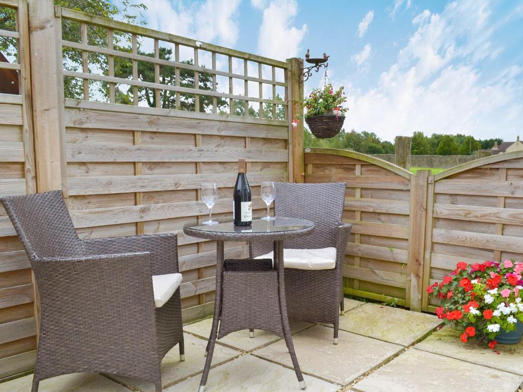 a patio with a table and chairs and a fence at Eagles Cottage in Corston