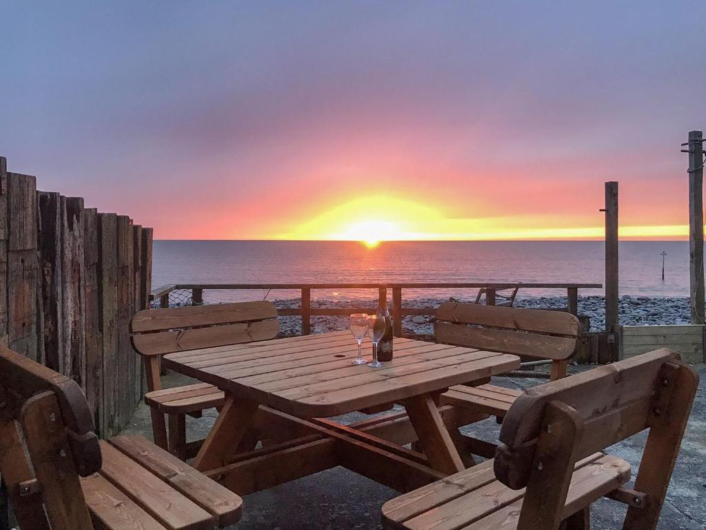 a wooden picnic table with two chairs and a sunset at Ystwyth House in Borth