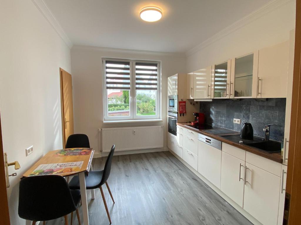 a kitchen with white cabinets and a table and a window at EXKLUSIVE Ferienwohnung in Einbeck, Top Lage! in Einbeck