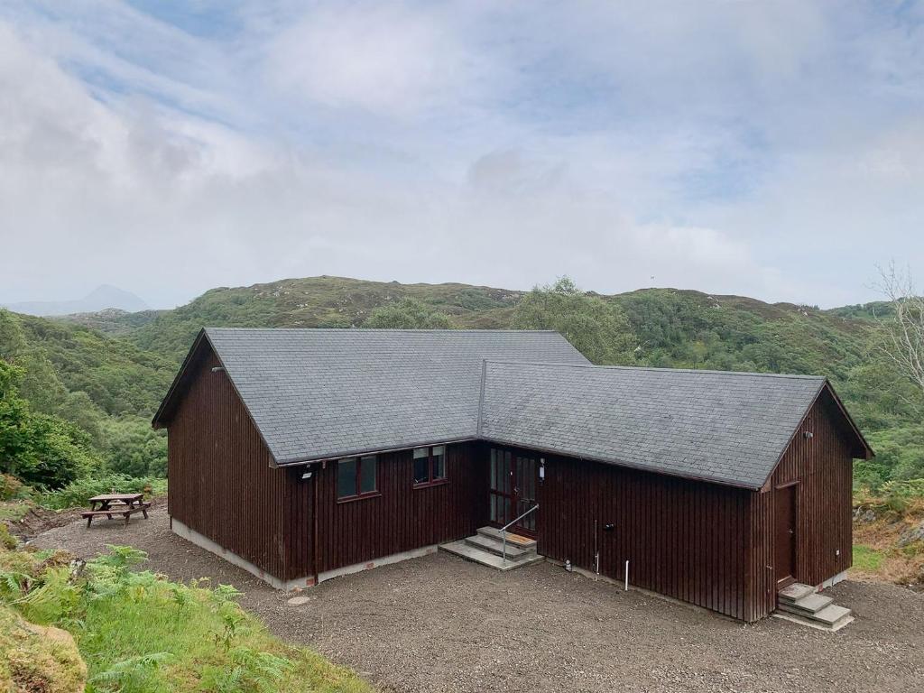 a large brown barn with a picnic table in front at Tigh Eilidh in Achmelvich