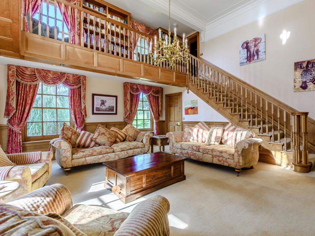 uma sala de estar com sofás e uma escadaria em Psalter Farmhouse em Skendleby
