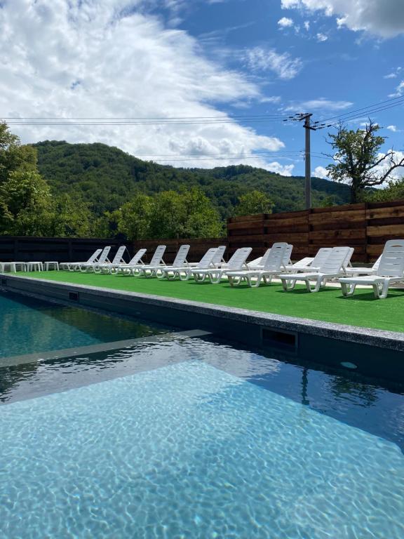 a swimming pool with white chairs and a swimming pool at Садиба Казка in Vizhenka