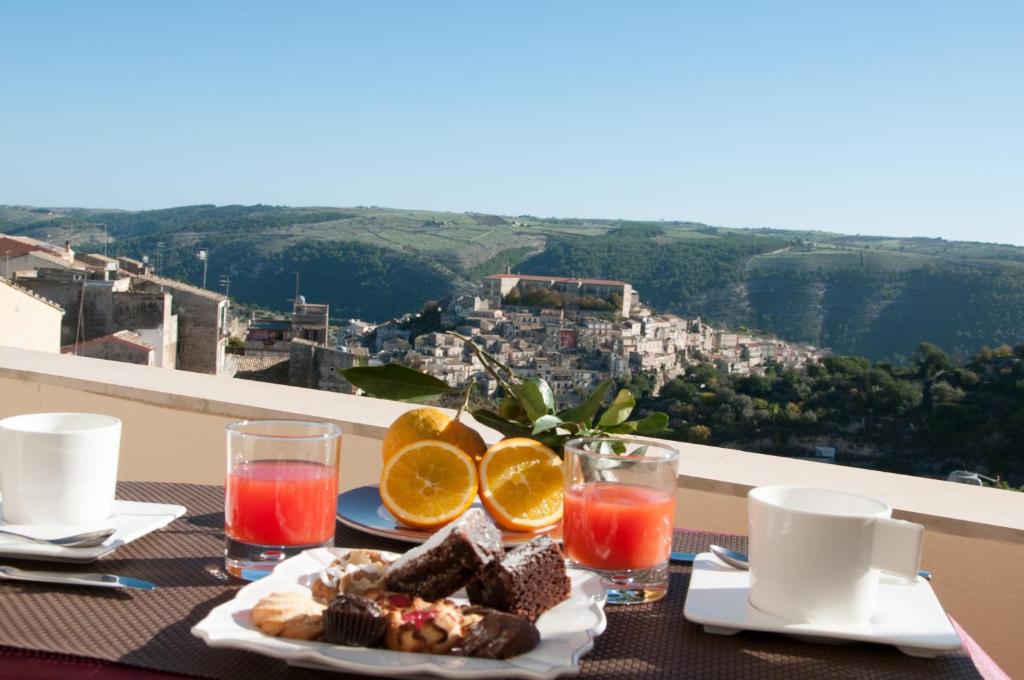 a table with plates of food and drinks on a balcony at Hotel La Dimora di Piazza Carmine in Ragusa