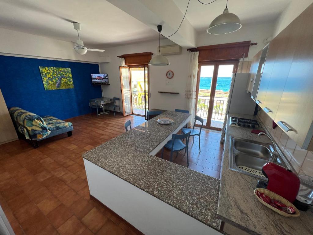 a kitchen with a counter top and a living room at Appartamento Vacanza Gioiosamare in Gioiosa Marea