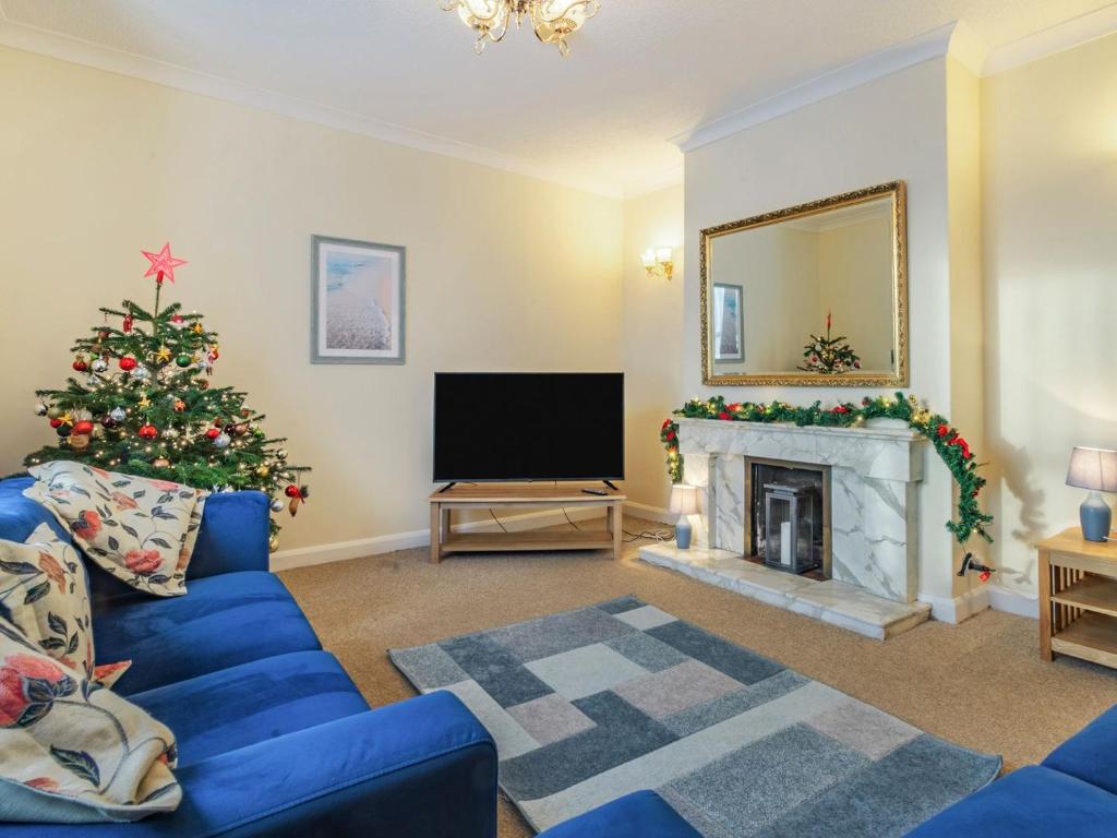 a living room with a christmas tree and a blue couch at West End Farm Lodge in Burton Agnes