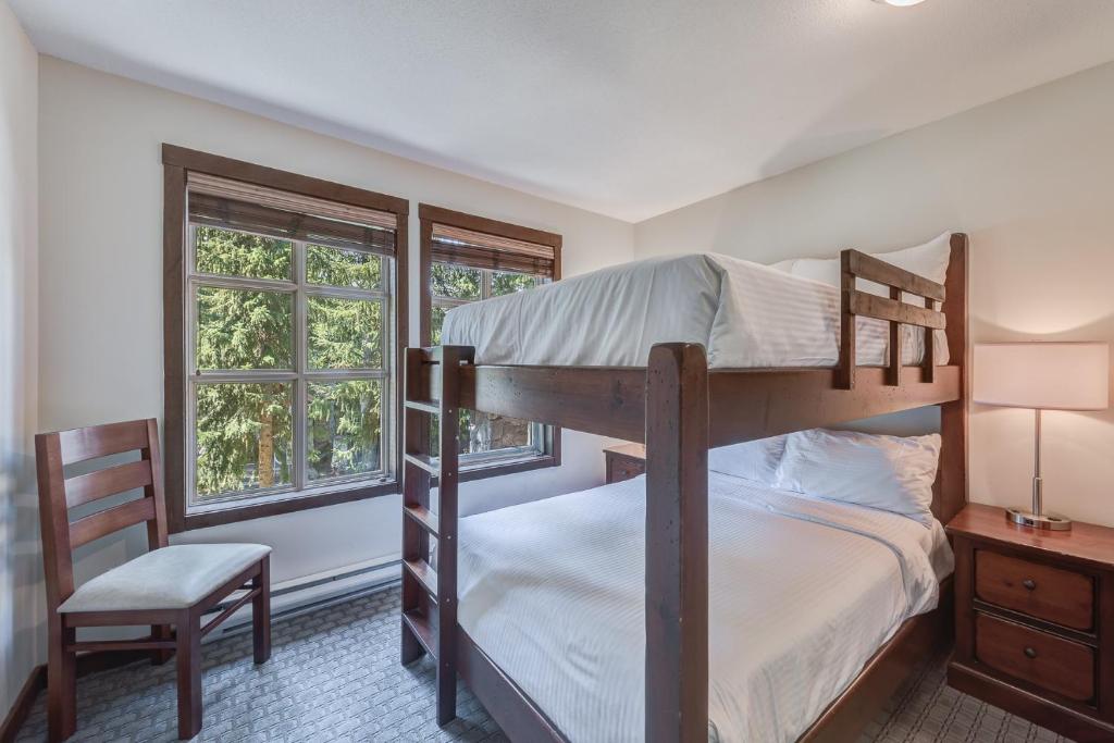 a bedroom with two bunk beds and a chair at Blackcomb Springs Suites by CLIQUE in Whistler