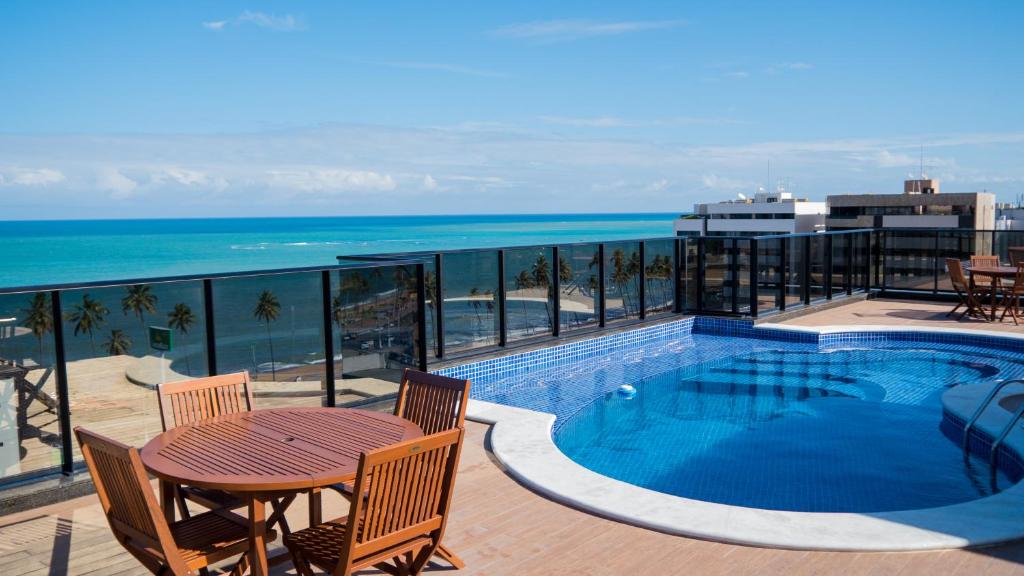 a balcony with a swimming pool and a table and chairs at Port Ville III in Maceió