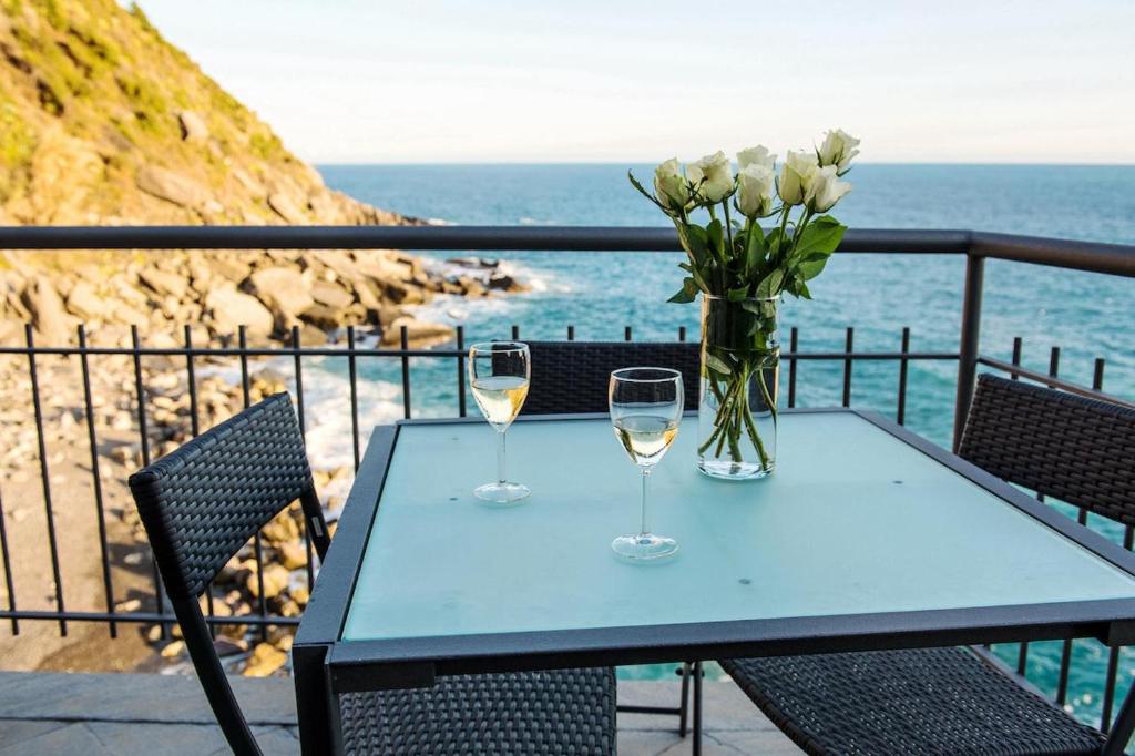 une table avec deux verres de vin et un vase de fleurs dans l'établissement Il Ciasso' Romantic Seafront Escape, à Vernazza