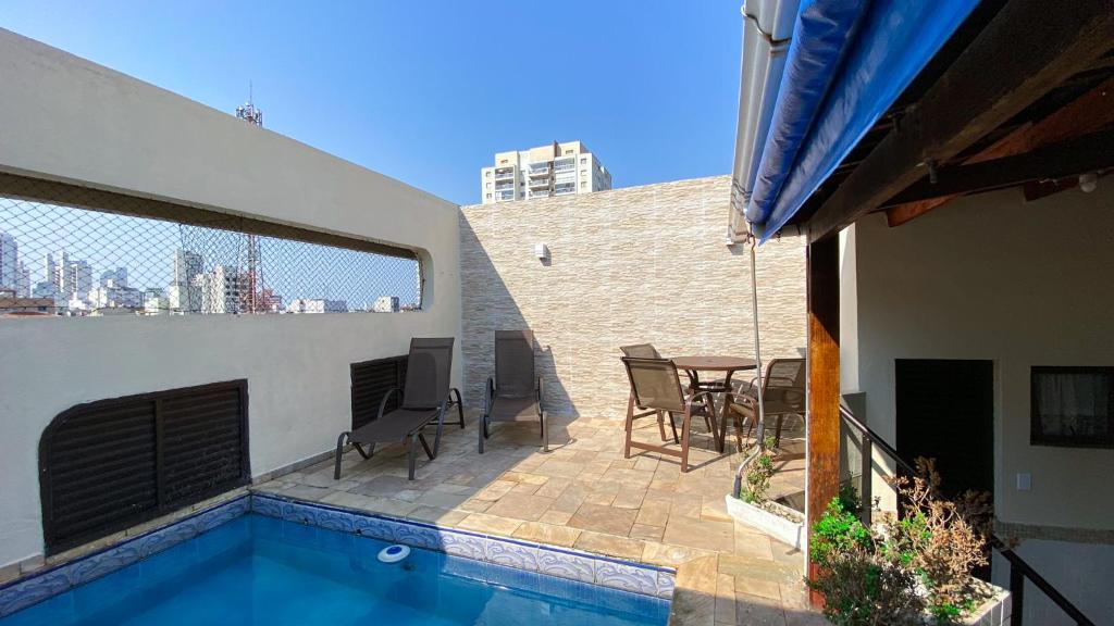 um pátio com uma mesa e cadeiras e uma piscina em Cobertura de 3 quartos com churrasqueira e piscina no Guarujá