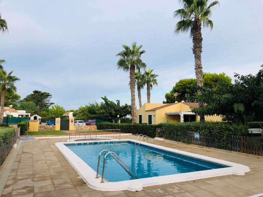 a swimming pool in a yard with palm trees at Sa Caseta d'Artrutx in Cala en Bosc