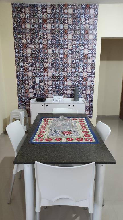 a table with white chairs and a rug on it at Casa de Temporada Aconchego in Macaé