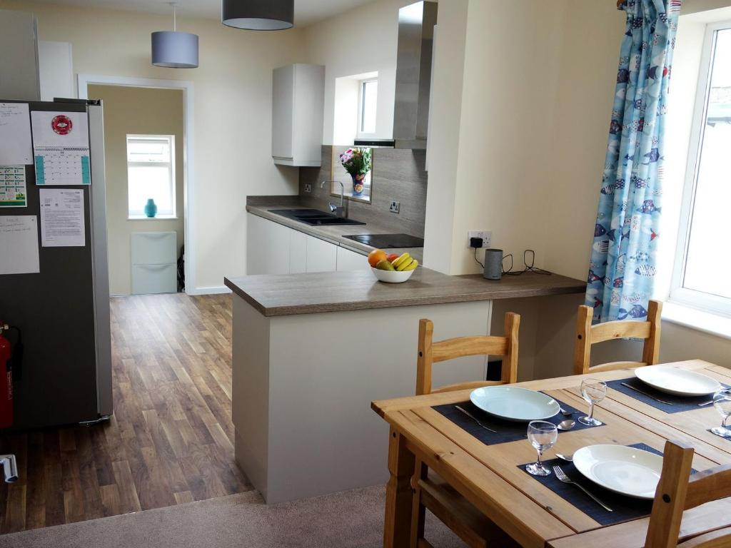 a kitchen with a wooden table and a kitchen with a refrigerator at Deany Apartment in Bridlington