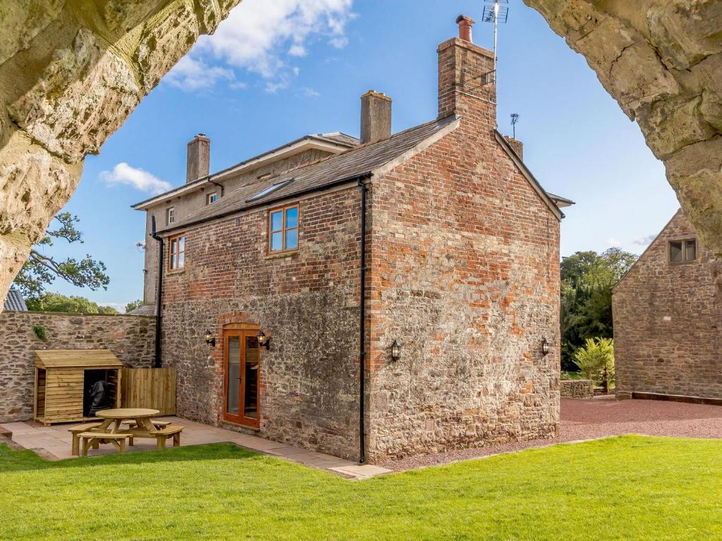 un viejo edificio de ladrillo con una mesa de picnic delante de él en The Old Laundry - Uk12136 en Hewelsfield