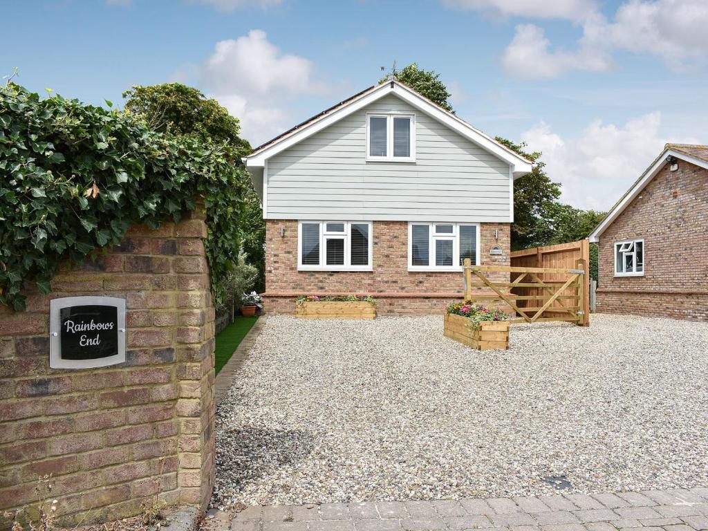 a house with a brick wall and a driveway at Rainbows End in Saint Lawrence