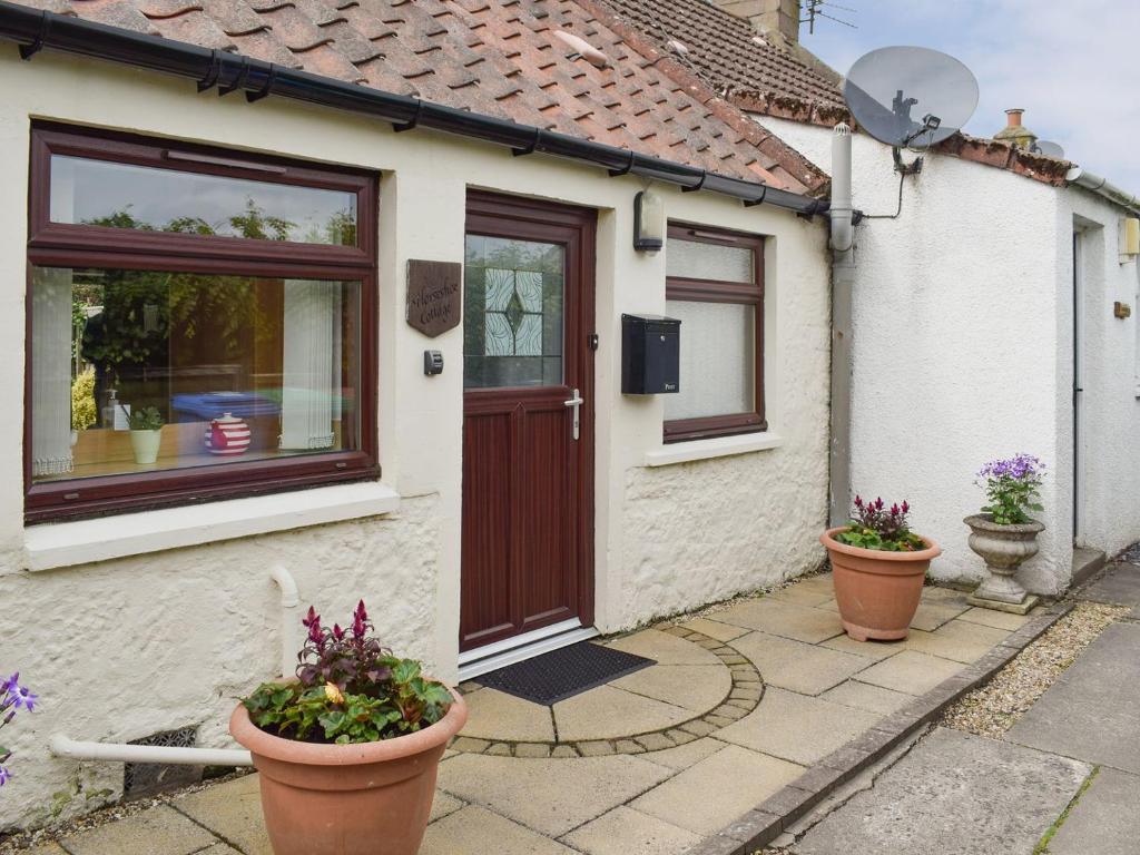 a house with two potted plants in front of it at Horseshoe Cottage in Fife