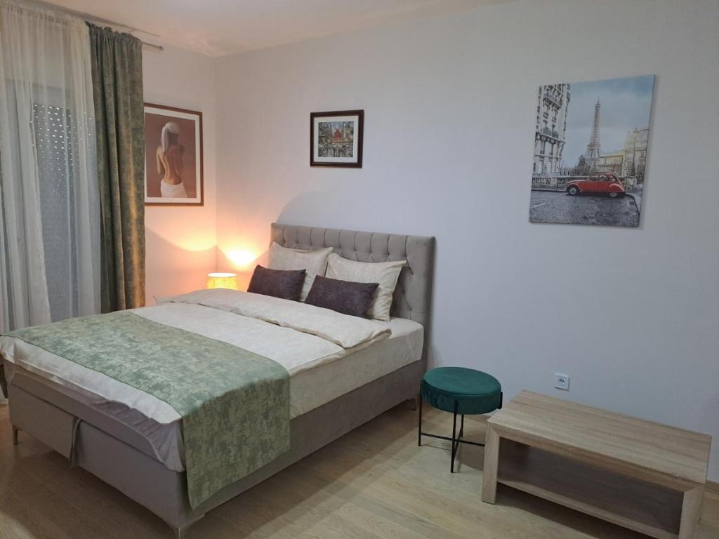 - une chambre avec un lit et un tabouret vert dans l'établissement Apartman City kvart, à Podgorica