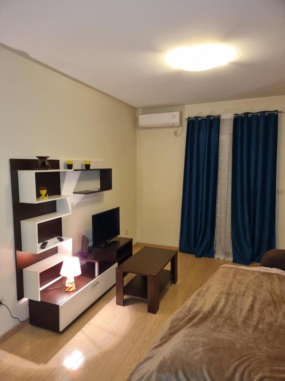 a bedroom with a bed and a desk with a television at Clarissa apartment City Kvart in Podgorica