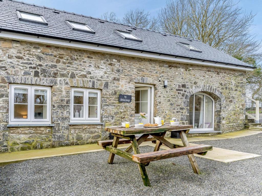 a picnic table in front of a stone cottage at Ty Draenog - Uk31653 in New Quay