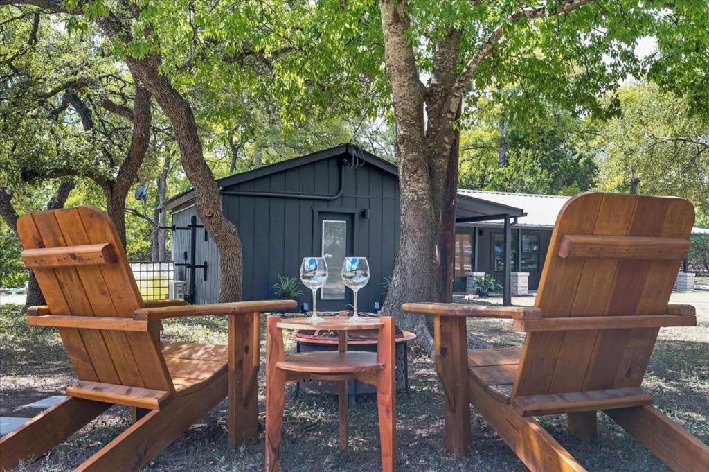 2 Holzstühle und ein Tisch mit Weingläsern in der Unterkunft Relaxing Alpaca Ranch Mins from Downtown Wimberley in Wimberley