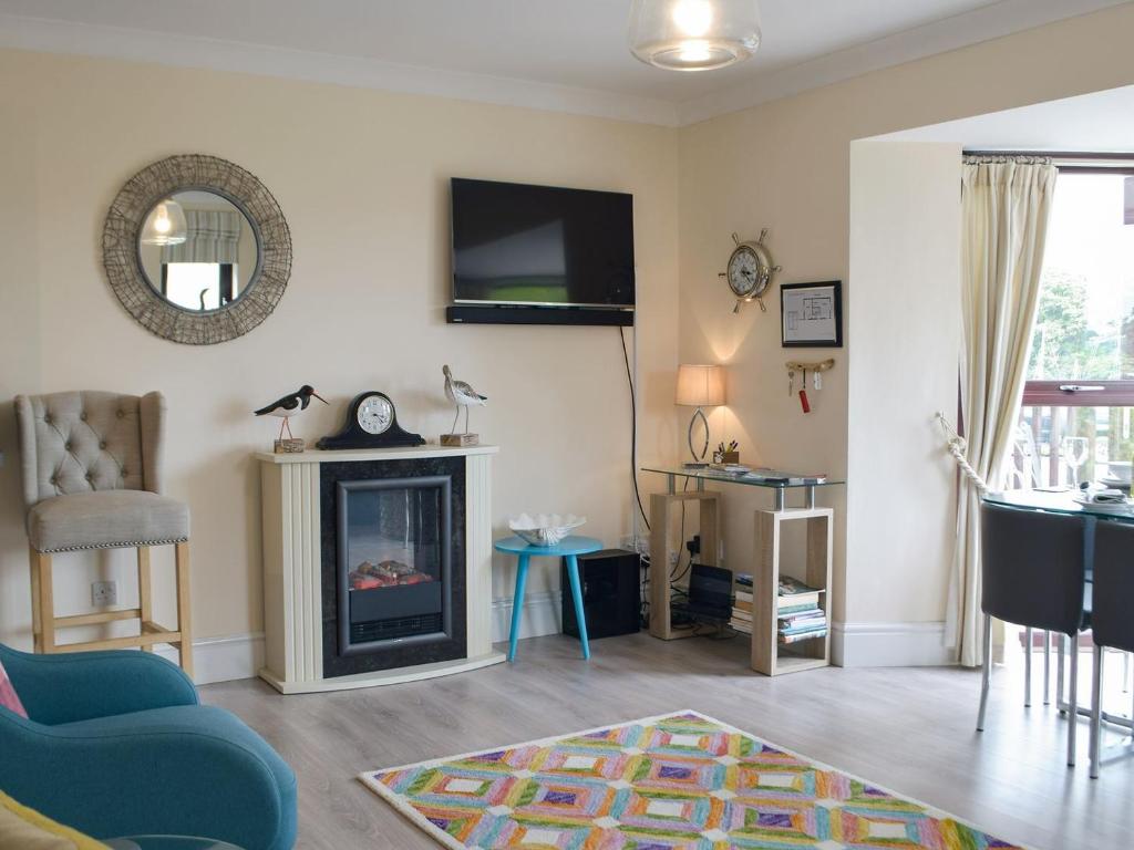 a living room with a fireplace and a tv on the wall at Neyland Marina in Neyland