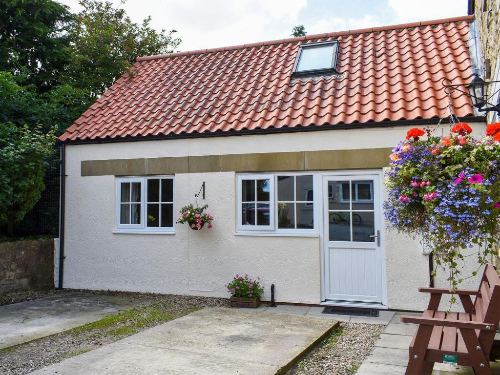 una pequeña casa blanca con techo rojo en Rosebank Cottage, en Aldbrough