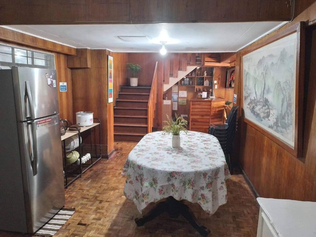 a kitchen with a table and a refrigerator and stairs at Amara Transient House in Baguio