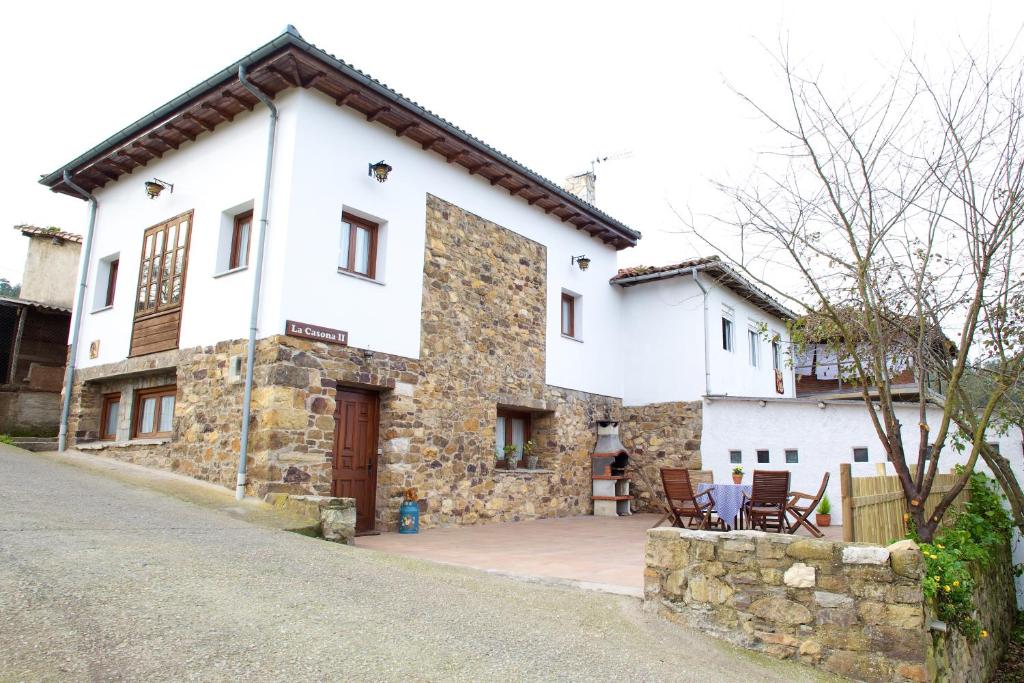 Casa blanca grande con un edificio de piedra en La Casona II de Pravia, en Pravia