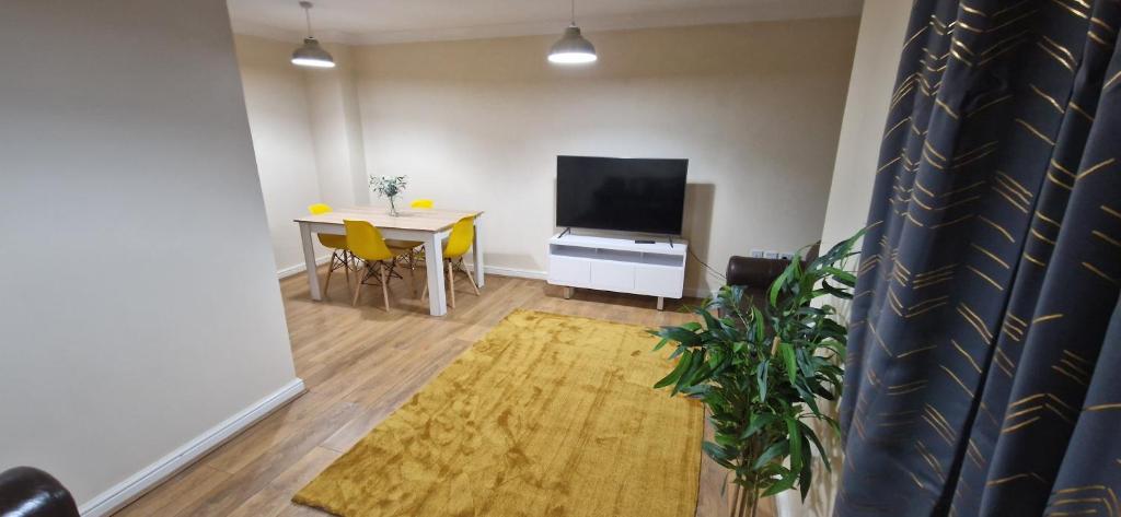 a living room with a television and a table with chairs at Dartford Cosy and Spacious 3 bedroom house Netflix and Sport Channels in Dartford