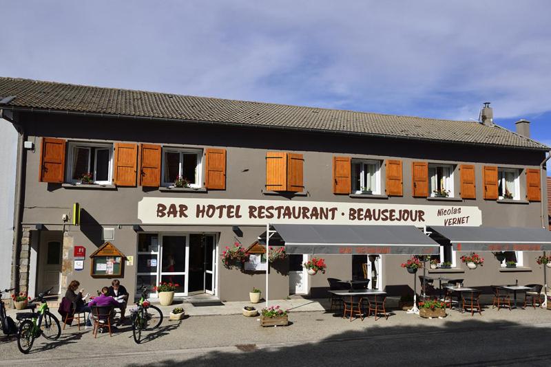 een bar hotel restaurant met mensen buiten zitten bij Maison VERNET - Hôtel Beauséjour in Le Béage