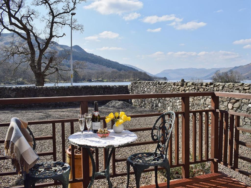 a table with wine glasses and flowers on a balcony at Lochearnside Lodge in Saint Fillans