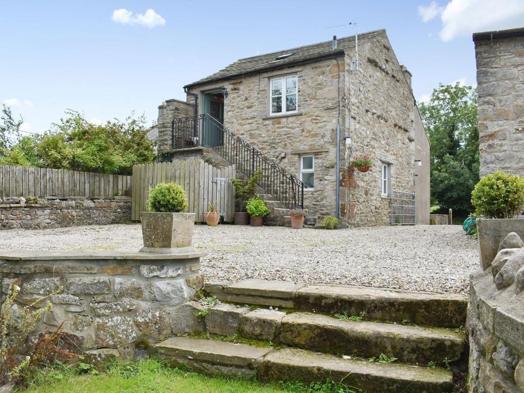 an old stone house with stairs in front of it at The Owlery At Aysgarth in Aysgarth