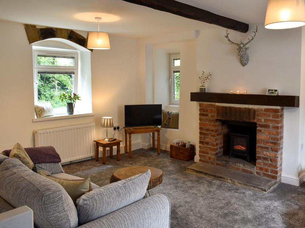 a living room with a couch and a fireplace at Beckside Cottage in Silsden