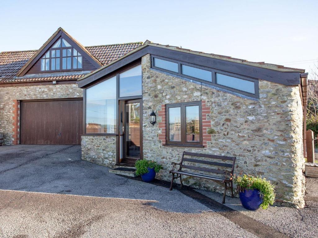 a stone house with a bench in front of it at Old Orchard Barn - The Annexe in Buckland St Mary