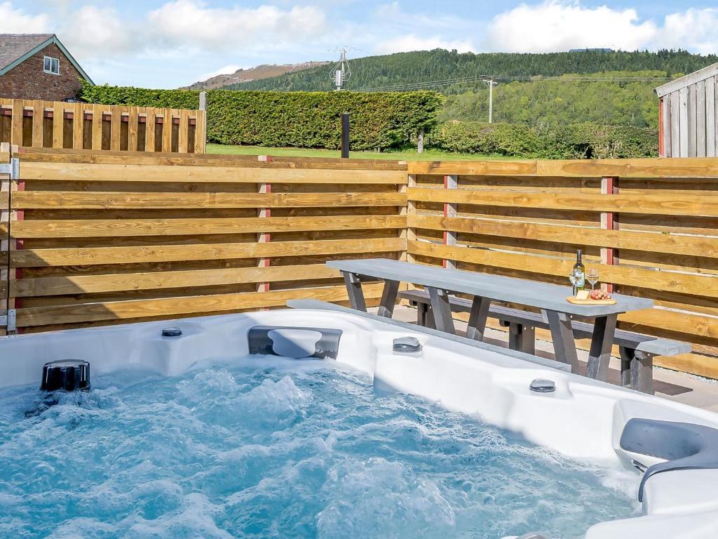 a hot tub with a picnic table next to a wooden fence at Cor Tarw - Uk12743 in Acrefair