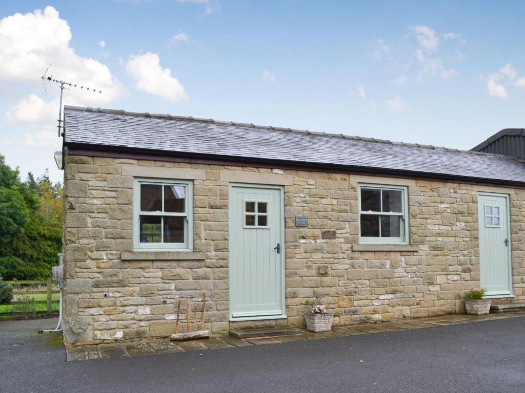 a stone cottage with two windows and a white door at Mill Force Cottage in Bowes