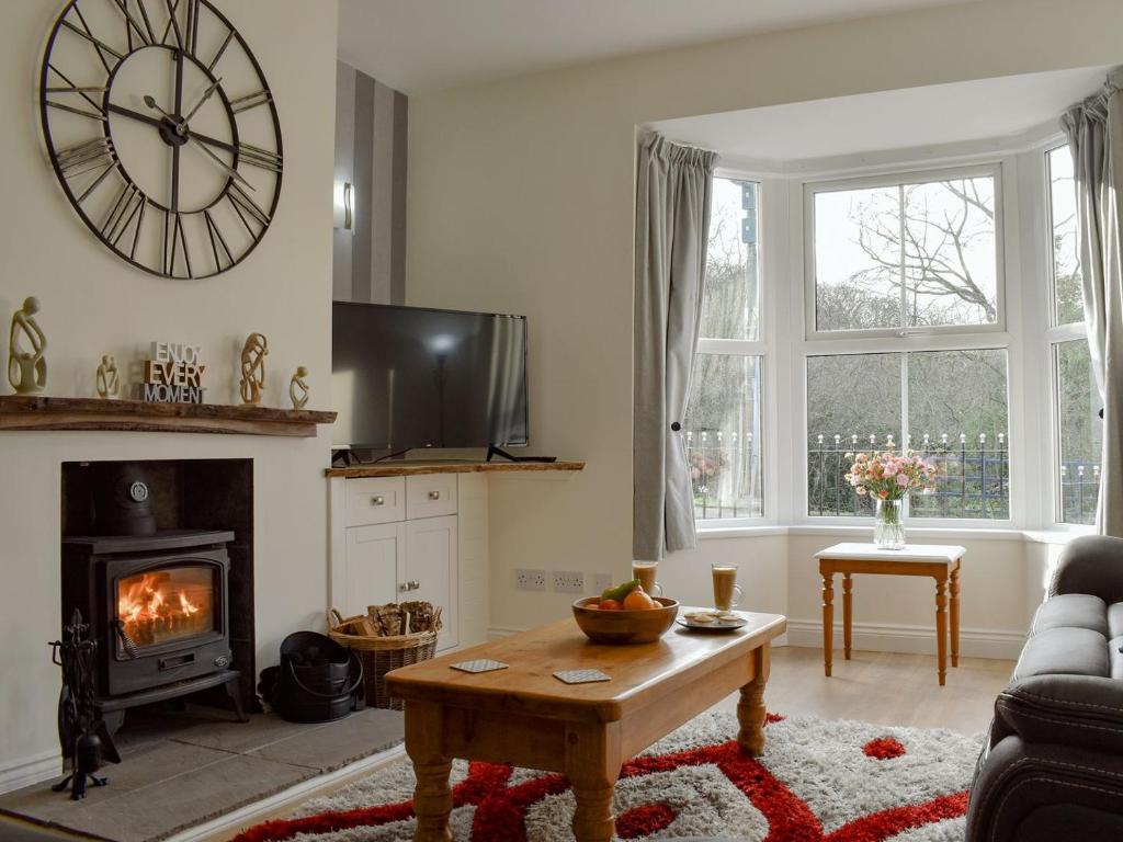 a living room with a fireplace and a clock on the wall at Bridge House in Loftus