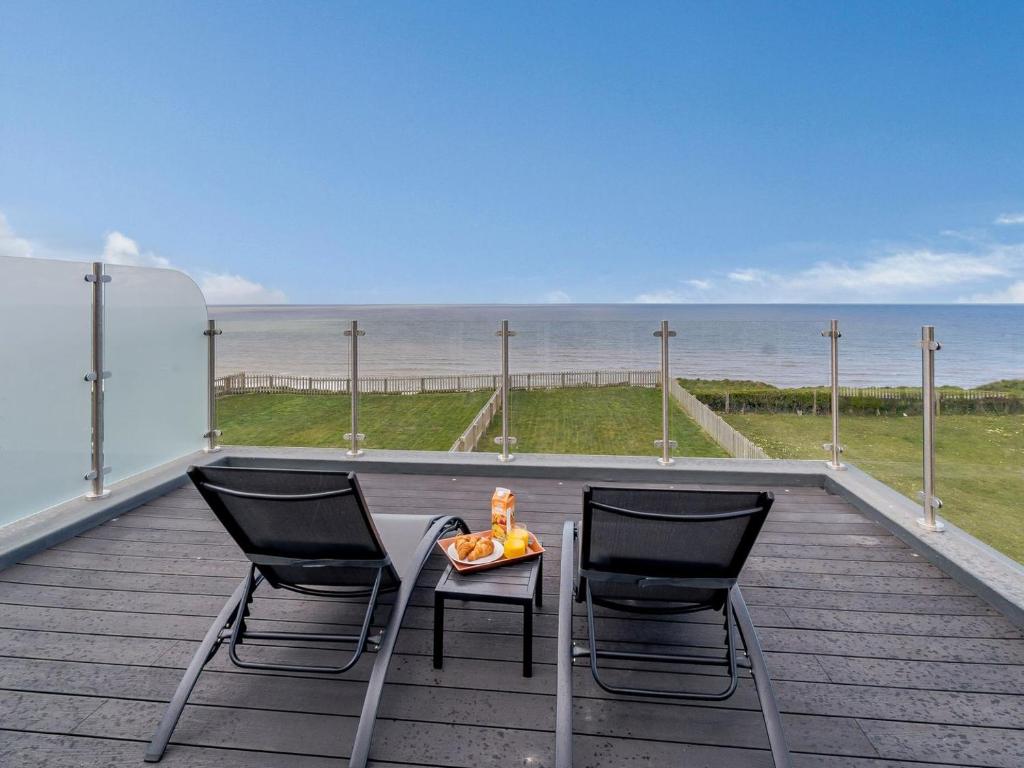 two chairs and a table on a deck with the ocean at Hunroe Brow in Reighton