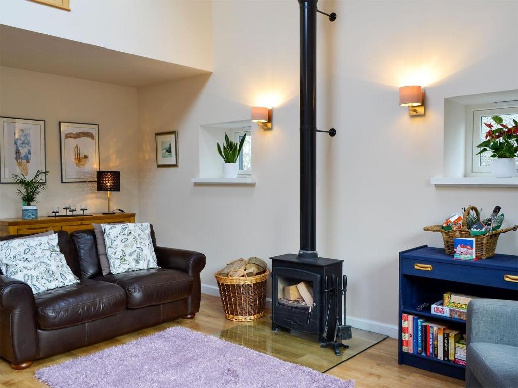 a living room with a couch and a stove at Birch Tree Cottage in Edzell
