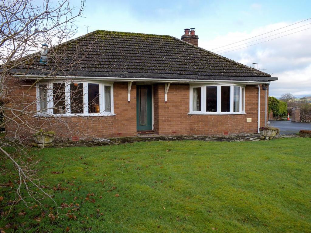 a brick house with a green lawn in front of it at Kinverley in Evenjobb