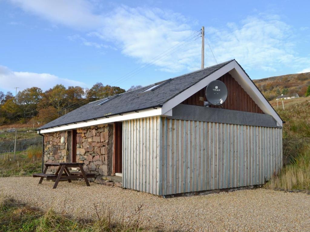 a small building with a black roof and a table at Mango Ponys Bothy - Uk31959 in Dibaig