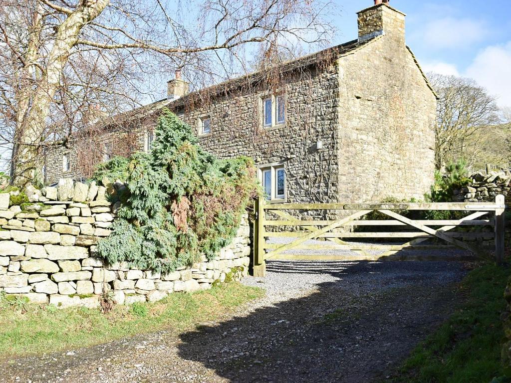 an old stone house with a gate and a stone wall at Southwaite in Outhgill