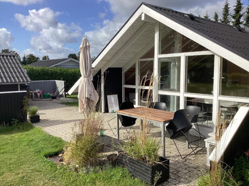 ein Haus mit einem Tisch und einem Sonnenschirm in der Unterkunft Holiday home Fårvang XIX in Fårvang