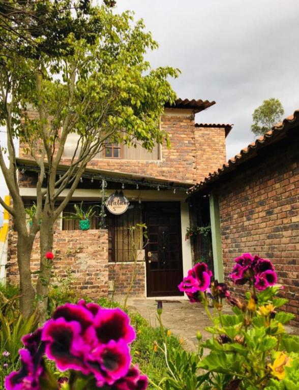 a brick house with pink flowers in front of it at Cabaña MALAVI Nobsa in Nobsa
