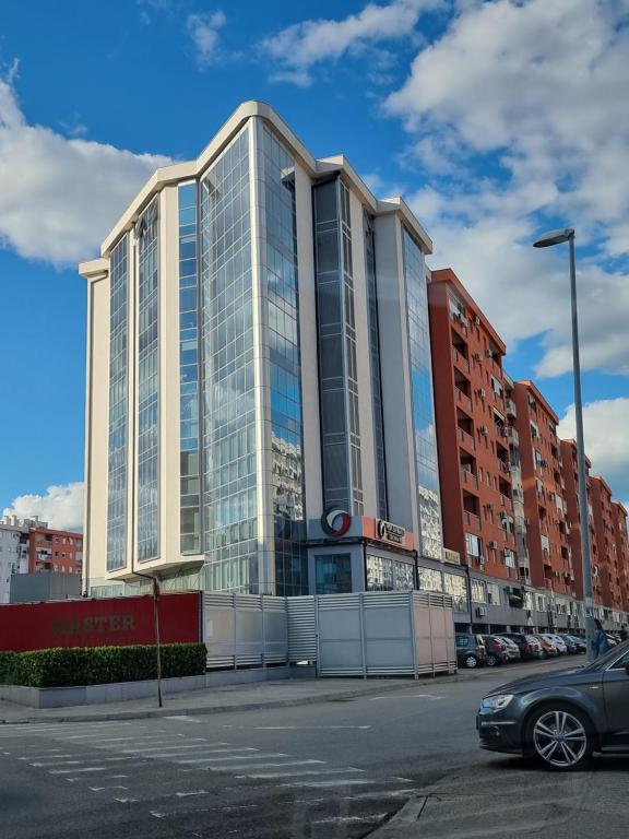 een groot glazen gebouw met een auto geparkeerd op een parkeerplaats bij Big apartment in Podgorica