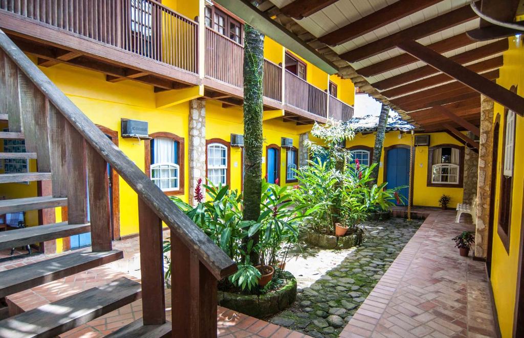 a yellow building with plants in a courtyard at Pousada Konquista in Paraty