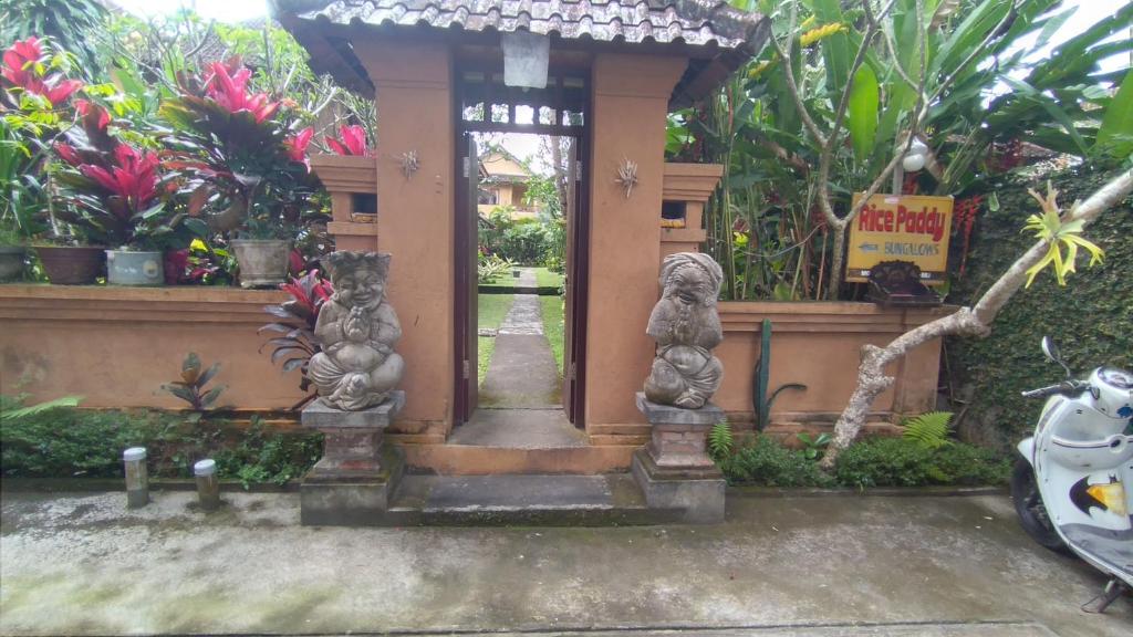 una entrada a un jardín con estatuas de animales en Rice paddy bungalow en Ubud