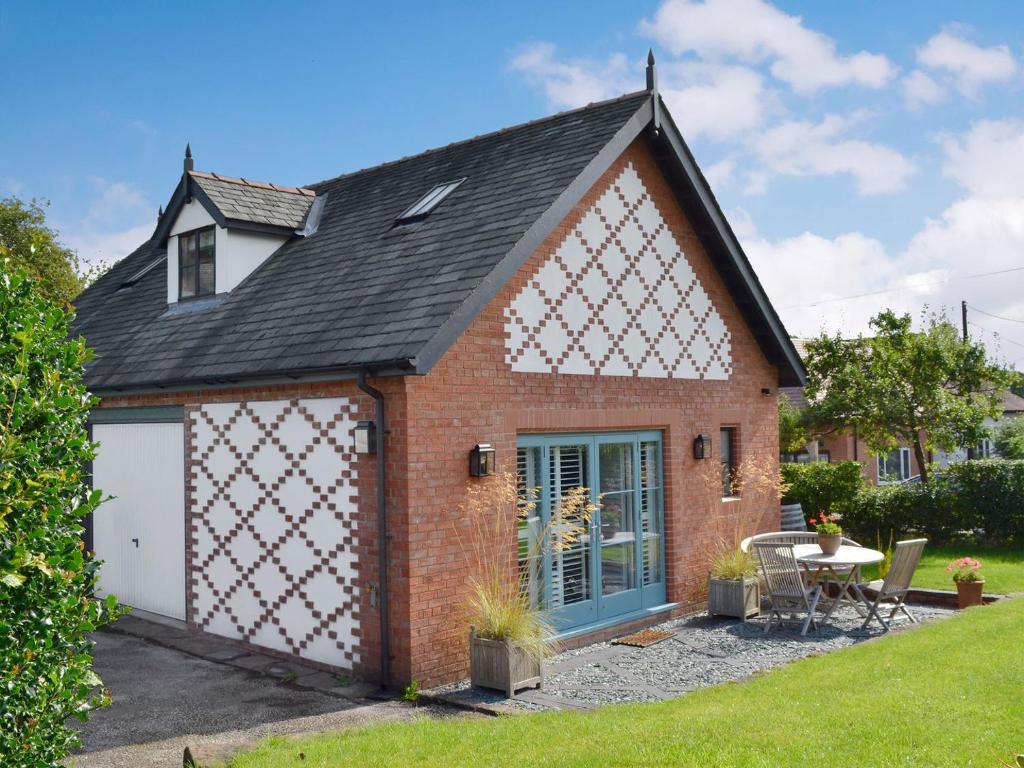 a small red brick house with a white garage at The Hen House At The Old Parsonage in Cote Brook